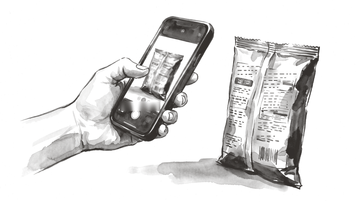 A hand holding a phone up to the back of a snack pouch.